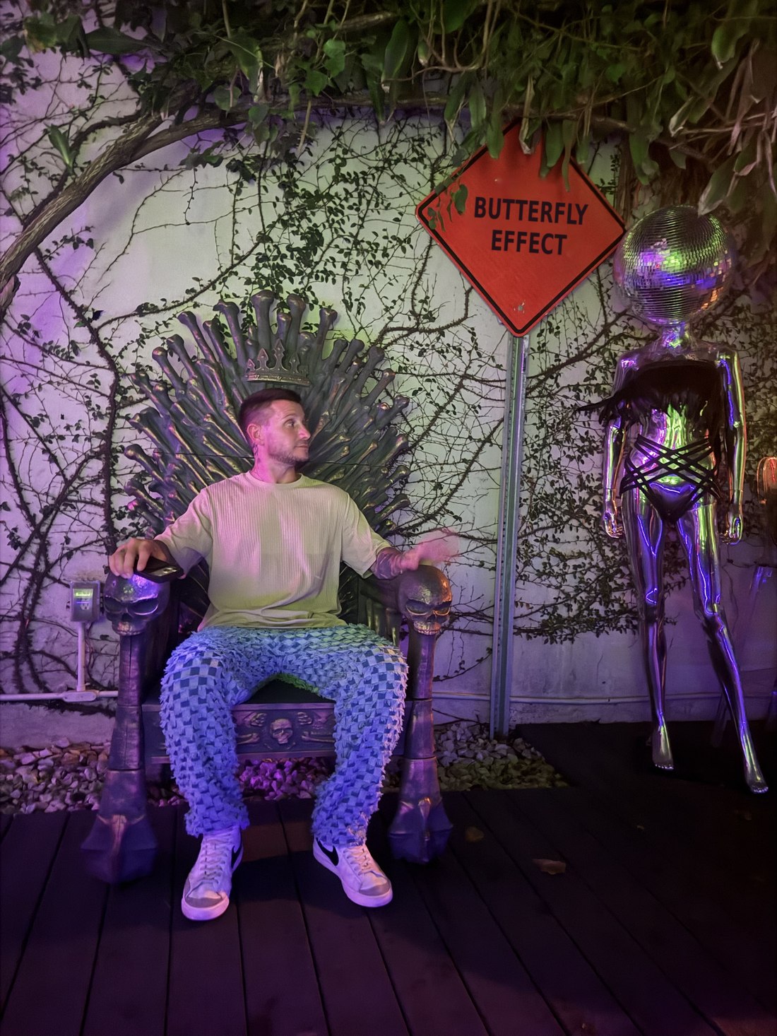 Justin Lubas seated beside a sign reading Butterfly Effect